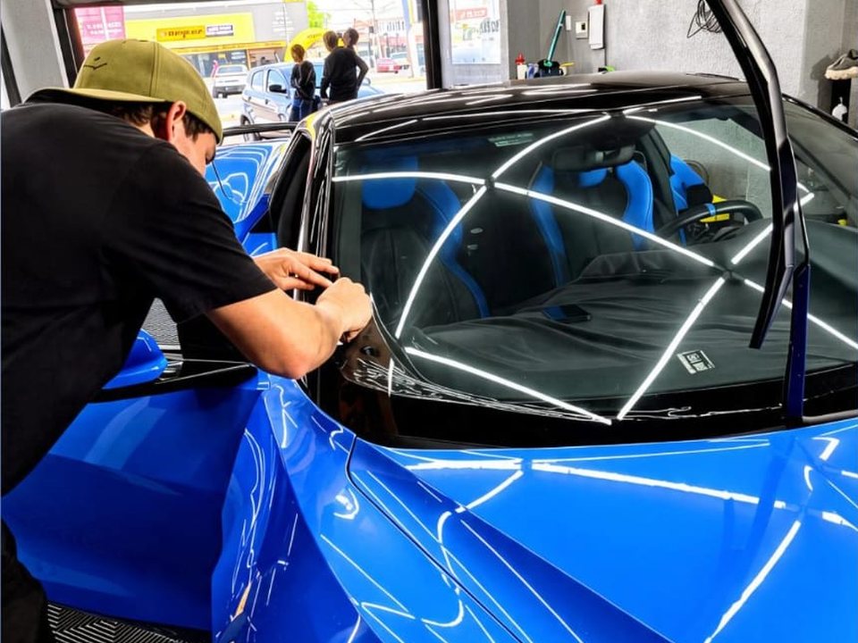 Instalador aplicando película no vidro de um carro